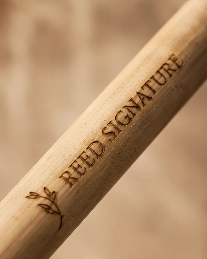 Gros plan macro sur la gravure laser du logo REED SIGNATURE sur une paille en roseau
